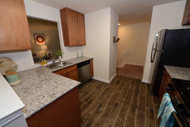 Harbortown Breeze kitchen photo showing wood grain tile flooring, maple cabinets, granite countertops and stainless steel appliances.