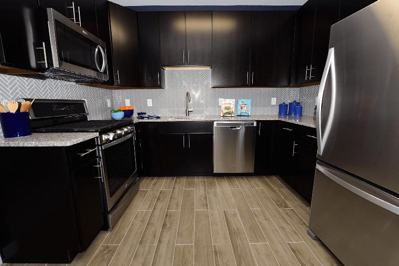 Hawthorne Square Kitchen photo showing the kitchen with espresso cabinets, stainless steel appliances, granite counter tops and laminate flooring. There are decorations on the kitchen counter.