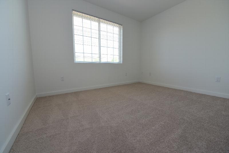 The Grove at Montgomery Bedroom photo with carpet flooring and a large window that allows natural light to enter the room.