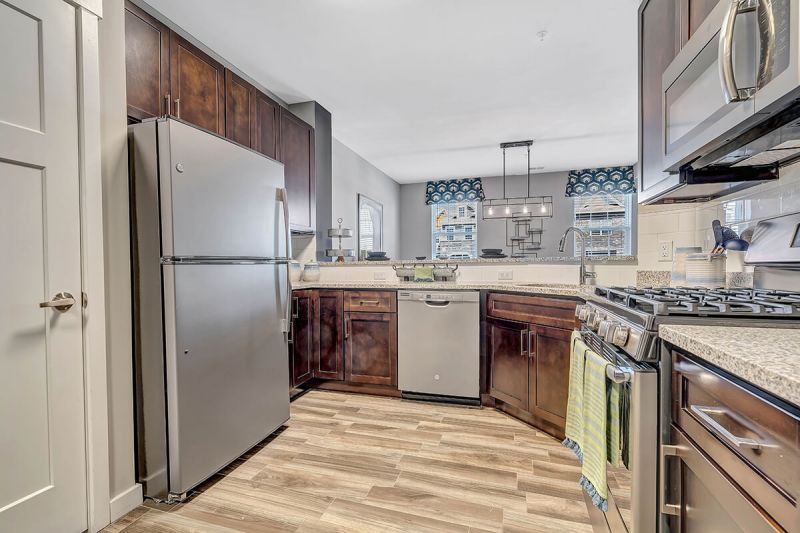 River Links interior photo of the kitchen, showing wood grain flooring, stainless steel appliance package, granite countertops and ample cabinet space.