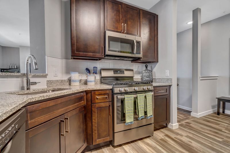 River Links interior photo of the kitchen, showing wood grain flooring, stainless steel appliance package, granite countertops and ample cabinet space.