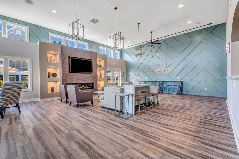 River links interior photo of the clubhouse main room, showing wood grain flooring, large fireplace with large screen tv, and multiple seating areas.