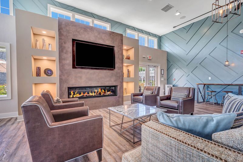 River links interior photo of the clubhouse main room, showing wood grain flooring, large fireplace with large screen tv, and multiple seating areas.