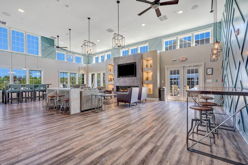 River links interior photo of the clubhouse main room, showing wood grain flooring, large fireplace with large screen tv, and multiple seating areas.