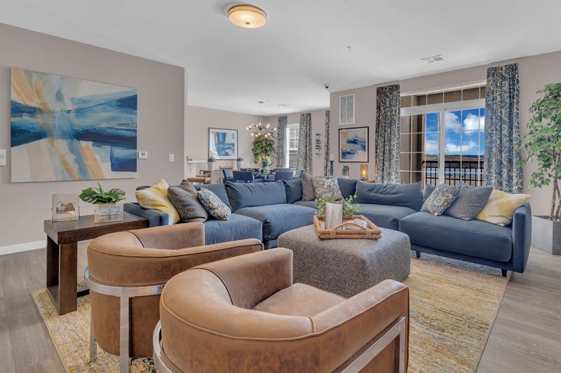 Interior photo of a model apartment at Bayonne Bay showing the main living area with luxury vinyl plank flooring, and a double door leading out to the balcony.