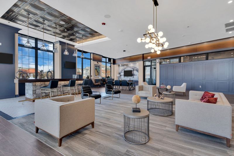Interior photo of The Club at Bayonne Bay showing the lounge area featuring multiple seating areas in a large decorated room with large windows overlooking the community.