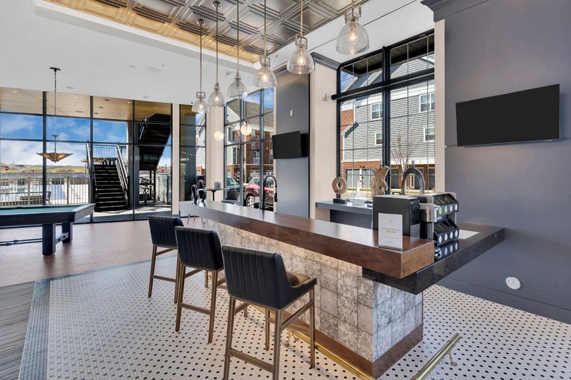 Interior photo of The Club at Bayonne Bay showing the lounge area featuring a bar area with seating, pool table with large windows overlooking the community.