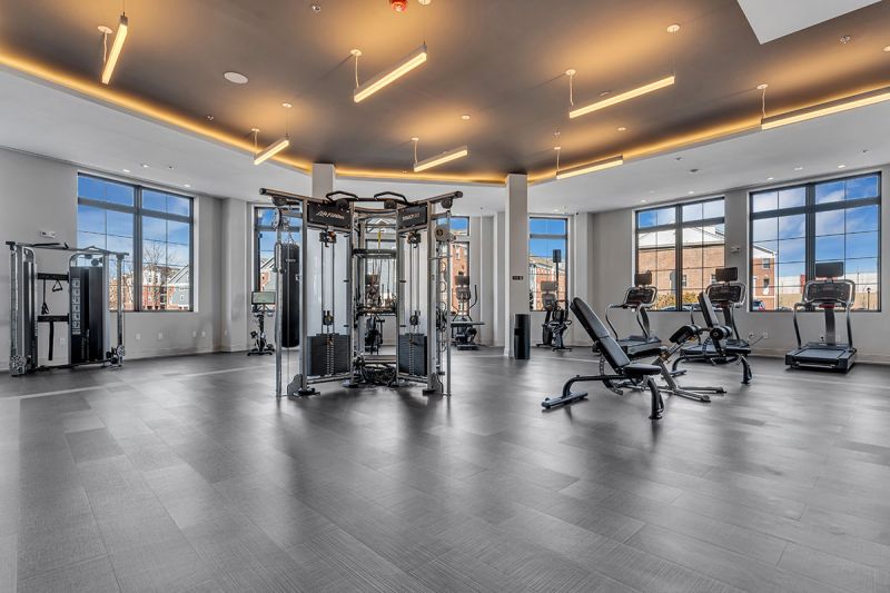 Interior photo of The Club at Bayonne Bay showing the fitness center with various stregnth training machines, treadmills and exercise bikes.