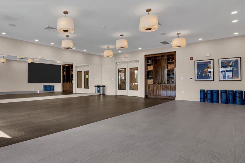 Interior photo of The Club at Bayonne Bay showing the Movement Studio, an open welcoming space with a huge mirror on one wall, for stretching, yoga and fitness.