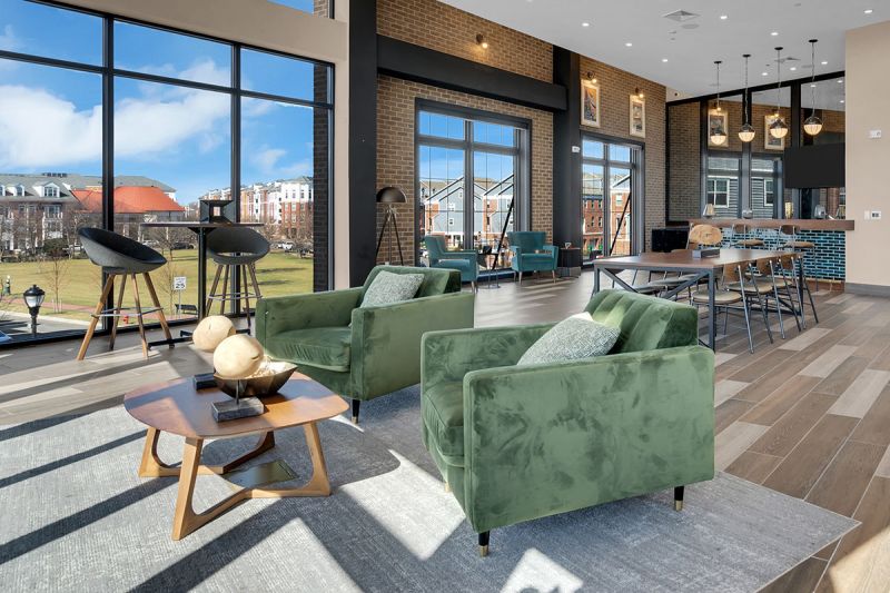 Interior photo of The Club at Bayonne Bay showing the Party Room, with multiple seating areas and large windows overlooking the community.