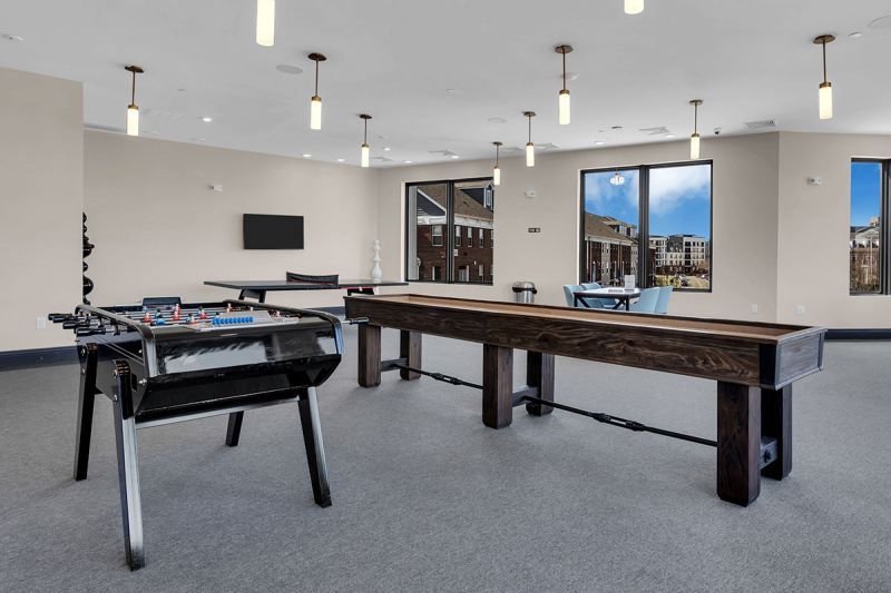 Interior photo of The Club at Bayonne Bay showing the Game Room featuring a ping pong table, shuffleboard and foozball.