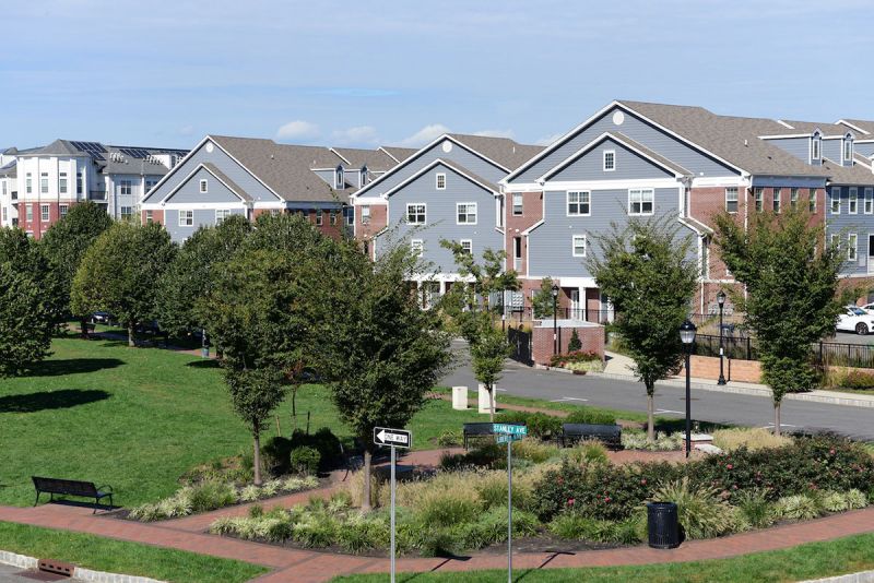 Photo of the park at Bayonne Bay featuring open green space, trees, paver walking path and a landscaped seating area.