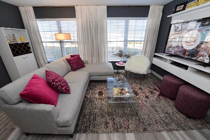 Sun Valley Plaza photo of a living area with a sectional couch and a wall mounted TV. There is a chair and two ottomans for additional seating.