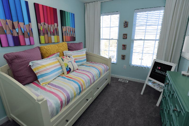 Sun Valley Plaza photo of a kid’s bedroom showing a daybed with storage below and a dresser. The room has plush wall to wall carpeting and two windows to allow for natural light.