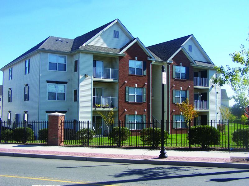 Meridian Square Exterior showing a 3 story apartment building with cream siding and lush landscaping.