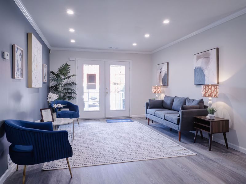 Photo of a renovated living room at Meridian Square showing new luxury vinyl plank flooring, fresh new paint, with a couch and several chairs for relaxing.