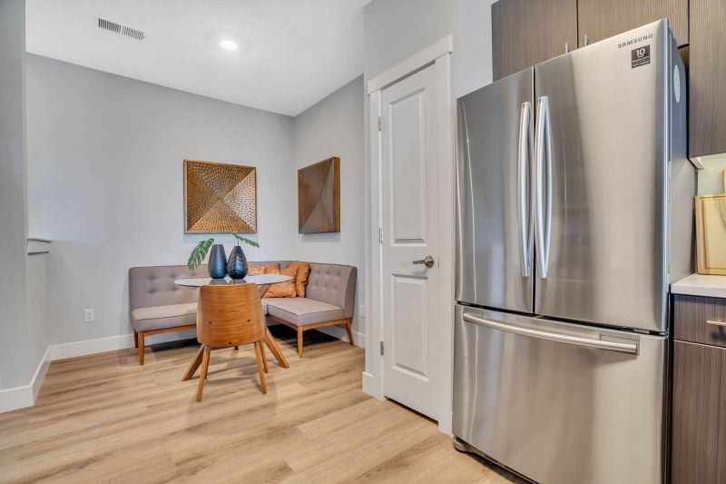 Interior photo of the eat in kitchen area in a typical apartment at Ewing Town Center, showing stainless woodgrain plank flooring and a comfortable table with bench and chairs.