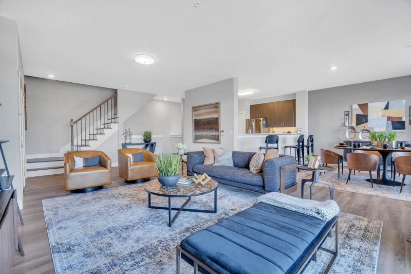 Interior photo of the main level living space in a tyical apartment at Ewing Town Center, showing a spacious living room & Dining room. There is a breakfast bar open to the kitchen. Stairs leading to the second floor living area are shown.
