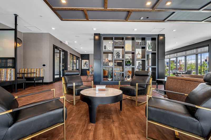 Interior photo of the community room at the clubhouse at Ewing Town Center with laminate woodgrain flooring, multiple seating areas for congregating.