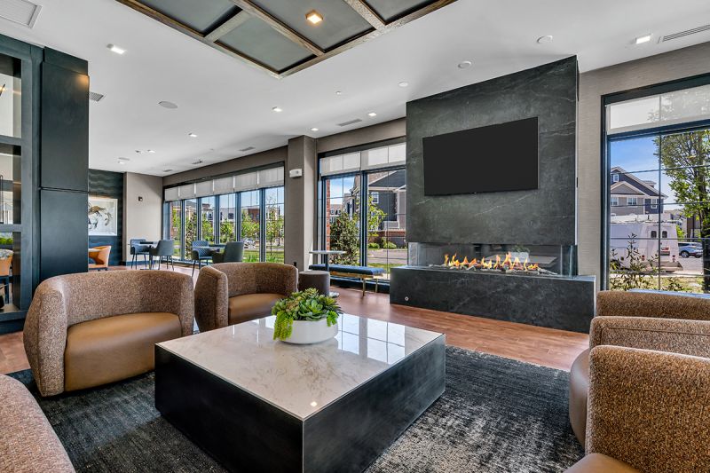 Interior photo of the community room at the clubhouse at Ewing Town Center with laminate woodgrain flooring and a luxurious seating area in front of the large gas fireplace with big screen tv above.