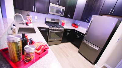 Grove Crossing kitchen photo showing espresso cabinets, stainless steel appliances and laminate flooring. There are several decorations on the kitchen counter.