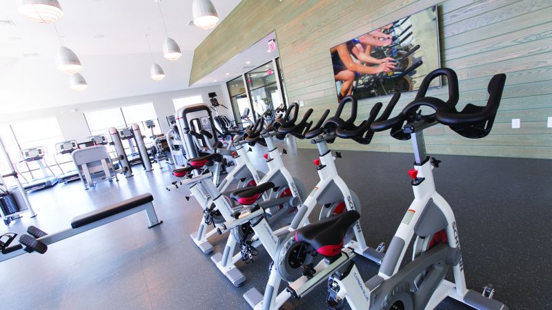 Grove Crossing Gym photo showing several treadmills, ellipticals, and exercise bikes. There are other various exercise machines.