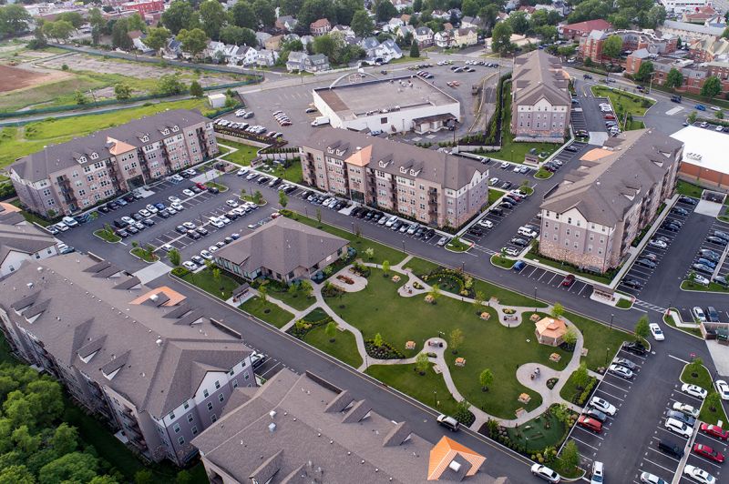Grove Crossing Aerial Photograph showing the Clubhouse and apartment buildings. There are several bushes and trees highlighting the landscape. The city around the complex can be seen in the background.