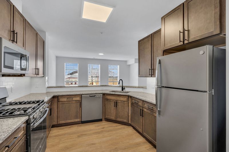 Interior photo of Amwell Terrace showing the kitchen with luxury vinyl woodgrain flooring, new cabinets with granite countertops, and a stainless steel appliance package.