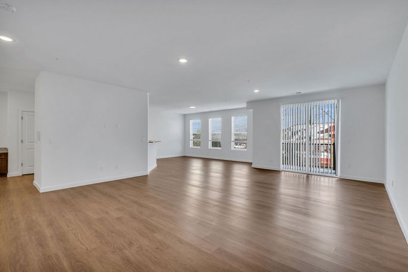 Interior photo of Amwell Terrace showing a large living area with luxury vinyl woodgrain flooring, a sliding glass door leading to a patio, and a dining room.