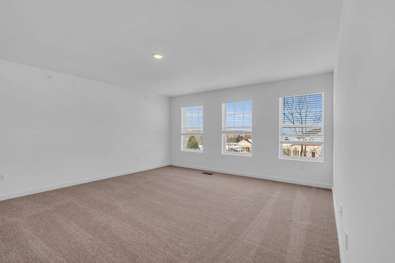 Interior photo of Amwell Terrace showing a large bedroom with wall to wall carpeting, and 3 large windows to allow for natural light.