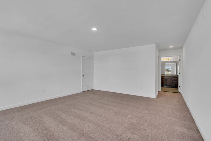 Interior photo of Amwell Terrace showing a large bedroom with wall to wall carpeting and the entrance to a primary bathroom