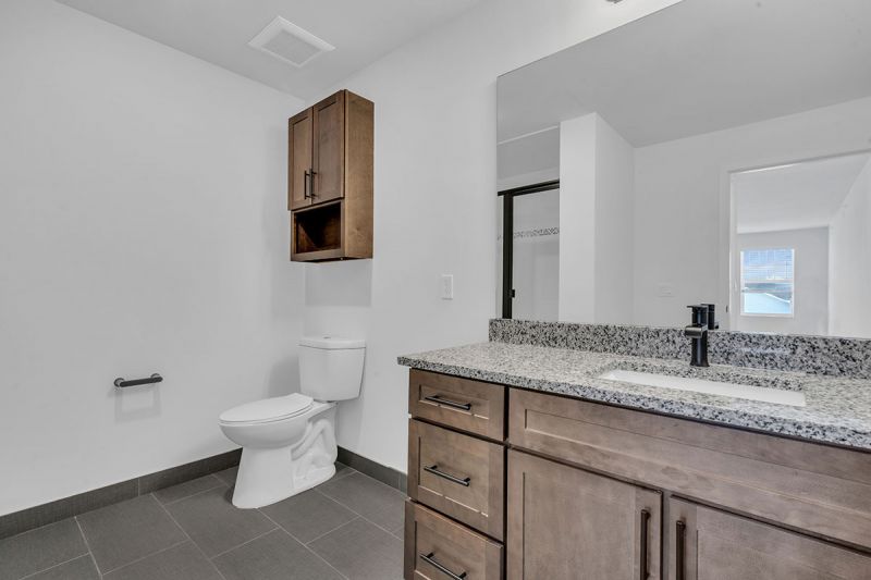 Interior photo of Amwell Terrace showing a large bathroom with tile flooring, large vanity and mirror, sink and toilet.