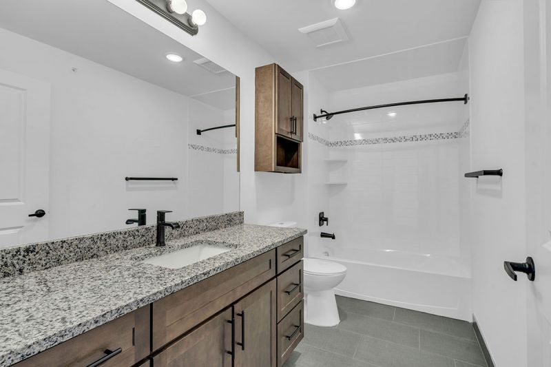 Interior photo of Amwell Terrace showing a large bathroom with tile flooring, large vanity and mirror, sink, toilet with medicine cabinet above and a bathtub..