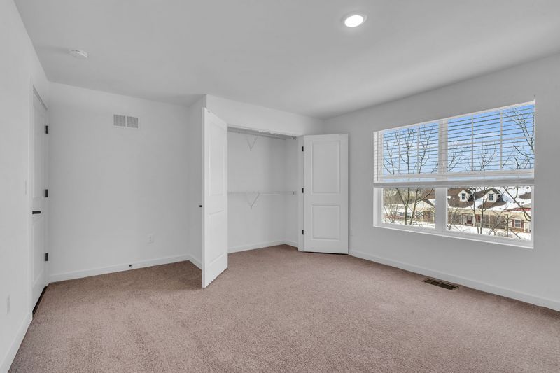 Interior photo of Amwell Terrace showing a bedroom with wall to wall carpeting, closet and a large double window for nautral light.