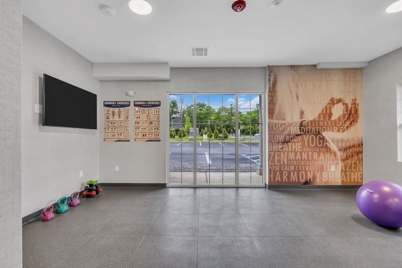 Interior photo of the movement studio at Amwell Terrace showing small weights, exercise balls, an open floor and a large screen tv on the wall.