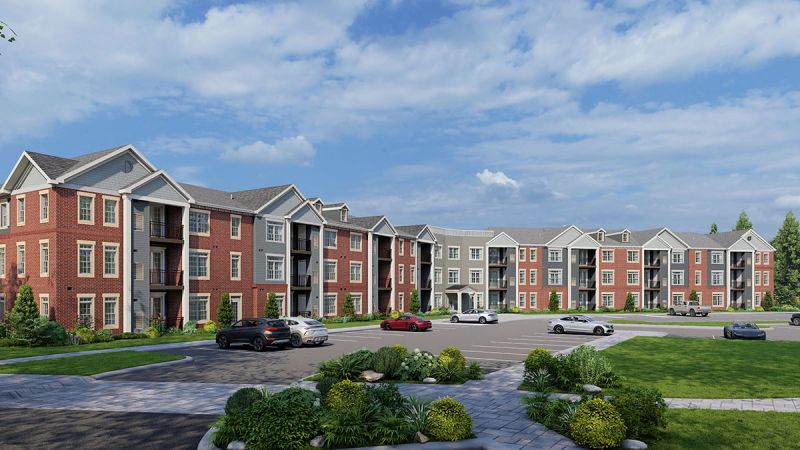 Artists rendering of Montgomery Meadows apartments, showing a 3 story apartment building, with gray siding, red brick, with cream and white trim. There are several balconies on each level, and the property is finished with lush landscaping.