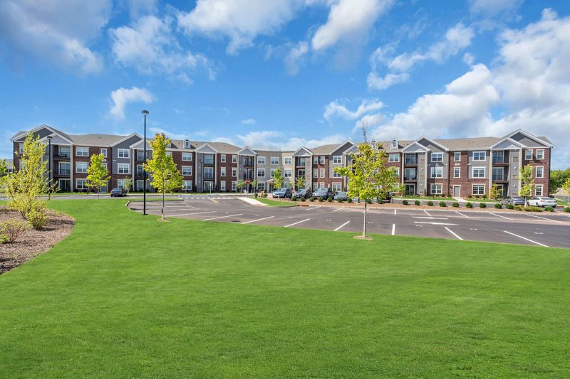Exterior photo of Meadows at Montgomery showing the building exterior with red brick, vinyl siding and white trim.