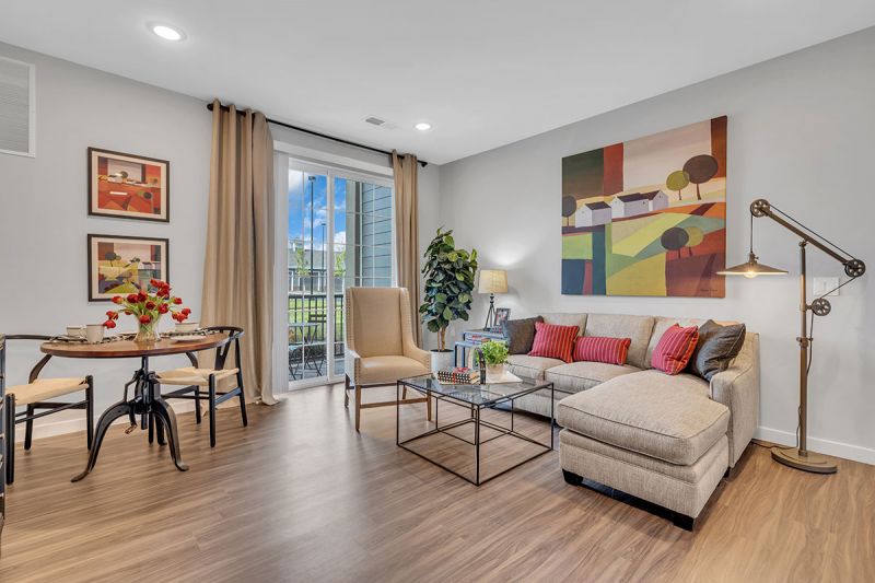 Interior photo of a Meadows at Montgomery apartment showing the living room area with luxury woodgrain vinyl tile flooring, a sitting area and cafe table dislpayed.
