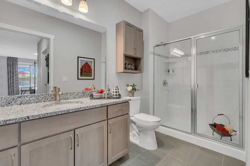 Interior photo of a Meadows at Montgomery apartment showing the primary bathroom with shower stall, large vanity with granite countertop, and luxury tile flooring.