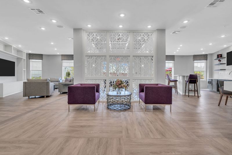 Interior photo of one of the community spaces at Meadows at Montgomery showing a luxury vinyl tile floor and multiple seating areas.