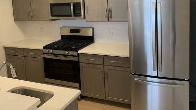 Rivendell Meadows Affordable interior photo showing the kitchen with luxury vinyl wood plank flooring, new cabinets, tile backsplash, stainless steel appliances and a breakfast bar.