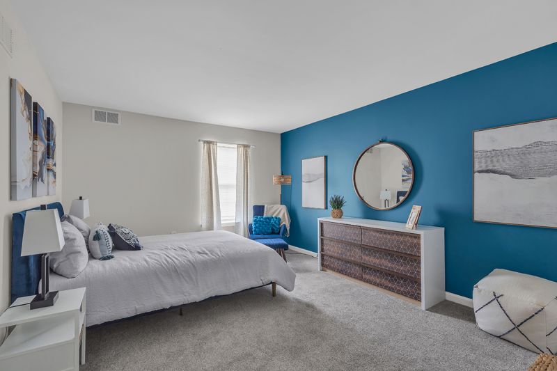 Interior photo of the bedroom at Meridian Terrace showing freshly painted walls, a bed, nightstands and dresser with wall-to-wall carpeting. A large window to allow for natural light.