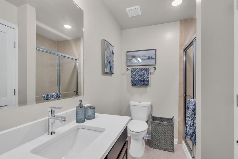 Interior photo of the bathroom at Meridian Terrace showing a stand-up shower with glass sliding door, a toilet and vanity with large mirror.