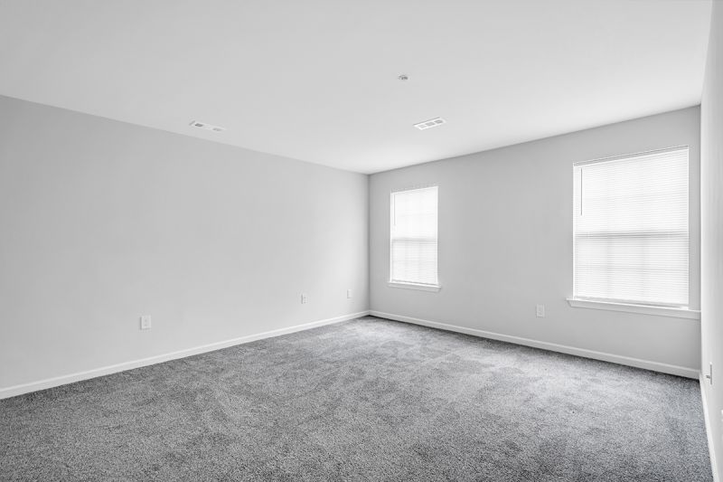 Interior photo of the bedroom at Meridian Terrace showing freshly painted walls, wall to wall carpeting and a double window to allow for natural light.