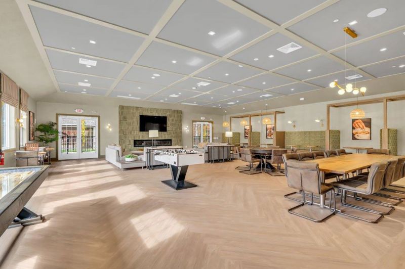 Interior photo of the clubhouse at Woodhaven showing the great room with multiple seating areas, large screen tv, gas fireplace and various table games.