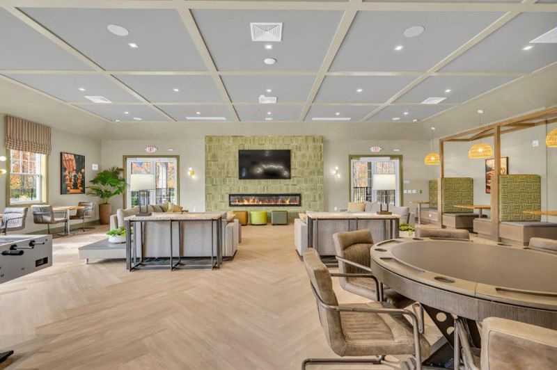 Interior photo of the clubhouse at Woodhaven showing the seating area in front of the large screen TV and gas fireplace.