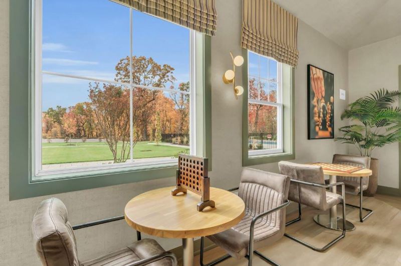 Interior photo of the clubhouse at Woodhaven showing the great room with multiple seating areas, large screen tv, gas fireplace and various table games.