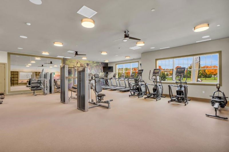 Interior photo of the gym inside the clubhouse at Woodhaven showing multiple cardio machines and weight machines.
