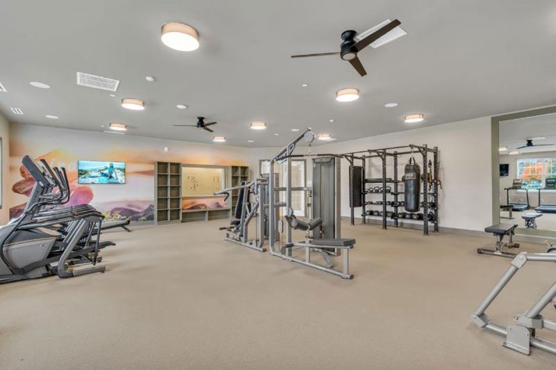 Interior photo of the gym inside the clubhouse at Woodhaven showing multiple cardio machines and weight machines.