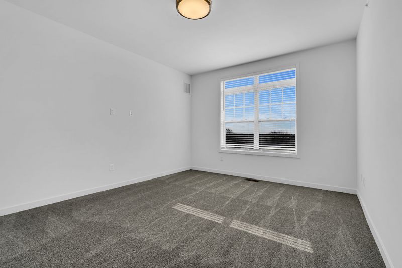 Photo of a bedroom at Edison Lights featuring lush wall to wall carpeting and a double window to allow for natural light.